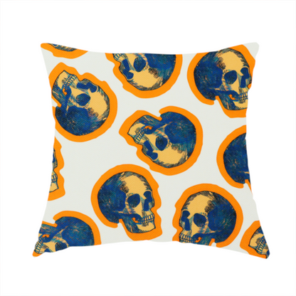 The fabric used to create this handmade cushion is a repeating pattern on an off-white background featuring distressed blue and yellow human skulls outlined in bright orange.