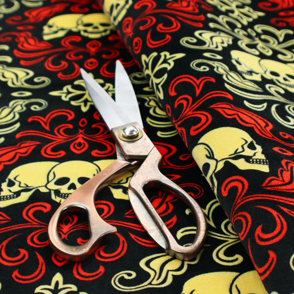 A black gothic damask pattern featuring ornate red and cream scrolling foliage, fleur-de-lis accents, and groups of three yellow human skulls.