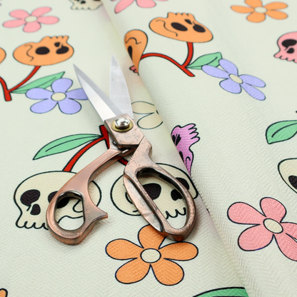 A light retro-style pattern featuring whimsical cherry pairs where the fruit is shaped like colourful skulls in shades of cream, pink, orange, and purple, accented by simple pastel flowers.