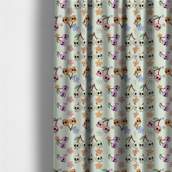 The fabric used to create these made-to-measure curtains is a light retro-style pattern featuring whimsical cherry pairs where the fruit is shaped like colourful skulls in shades of cream, pink, orange, and purple, accented by simple pastel flowers.