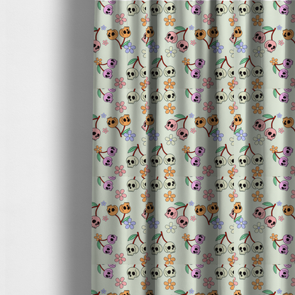 The fabric used to create these made-to-measure curtains is a light retro-style pattern featuring whimsical cherry pairs where the fruit is shaped like colourful skulls in shades of cream, pink, orange, and purple, accented by simple pastel flowers.