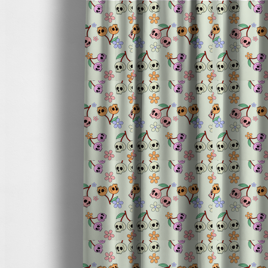 The fabric used to create these made-to-measure curtains is a light retro-style pattern featuring whimsical cherry pairs where the fruit is shaped like colourful skulls in shades of cream, pink, orange, and purple, accented by simple pastel flowers.