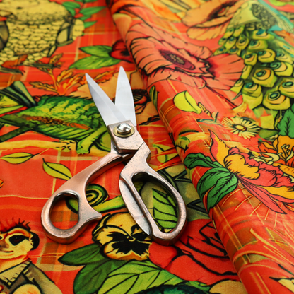 A busy, maximalist vintage-style fabric featuring a vibrant orange plaid background densely patterned with rock-and-roll animals in leather jackets and punk-inspired motifs, including cockatoos, flamingos, chameleons, a lion with a mohawk, meerkats, and lemurs intertwined with large flowers like poppies and pansies.