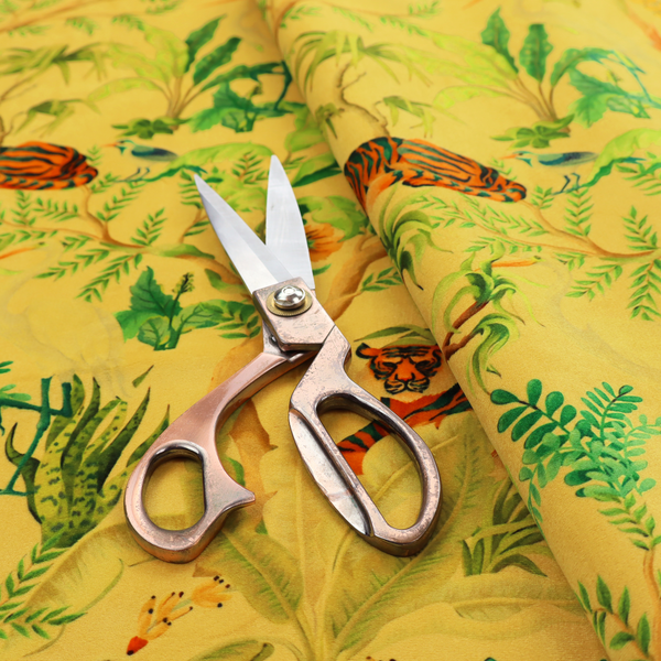 A vibrant yellow fabric featuring a dense tropical jungle pattern with tigers lounging on branches, toucans, herons, monkeys, and lush green foliage.   