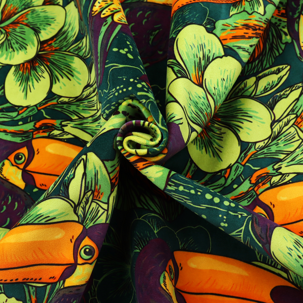 A dark green fabric densely patterned with toucans featuring large orange-and-yellow beaks, surrounded by glowing light green and orange tropical flowers.   
