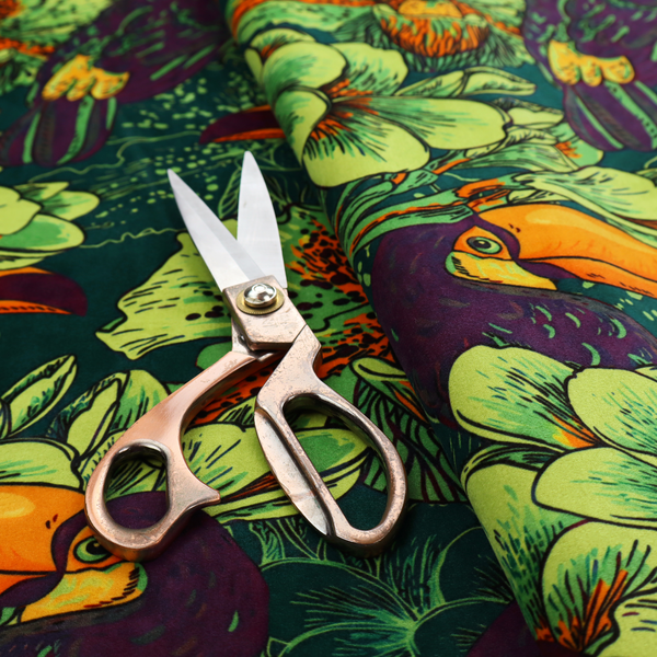 A dark green fabric densely patterned with toucans featuring large orange-and-yellow beaks, surrounded by glowing light green and orange tropical flowers.   