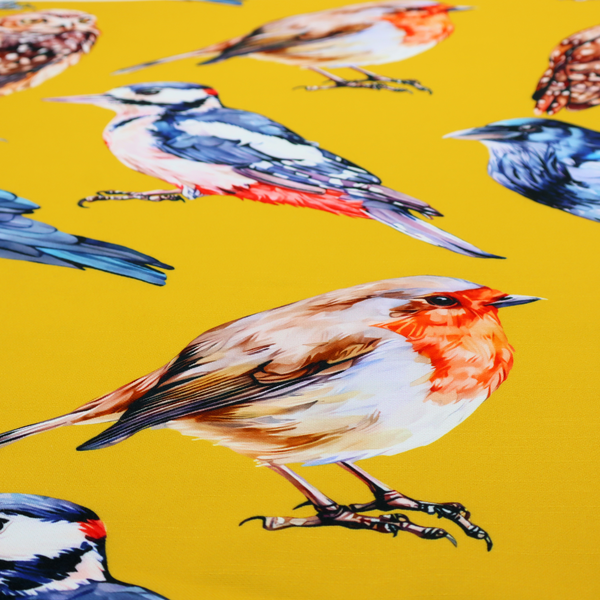 A vibrant yellow fabric patterned with a repeat design of various illustrated birds, including owls, robins, woodpeckers, and bluebirds
