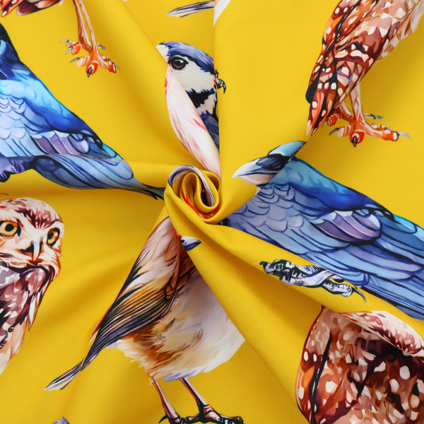 A vibrant yellow fabric patterned with a repeat design of various illustrated birds, including owls, robins, woodpeckers, and bluebirds