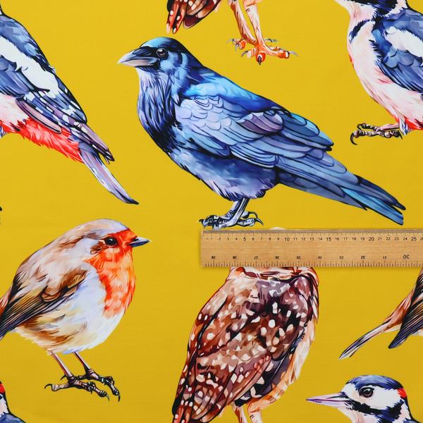 A vibrant yellow fabric patterned with a repeat design of various illustrated birds, including owls, robins, woodpeckers, and bluebirds