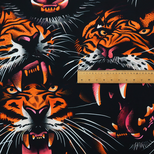 A dark patterned fabric featuring an aggressive, repeated motif of roaring tigers with bared fangs, detailed in vibrant orange, white, and pink against a black background.   