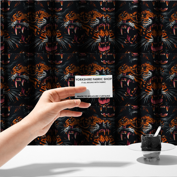 The fabric used to create these made-to-measure curtains is a dark patterned fabric featuring an aggressive, repeated motif of roaring tigers with bared fangs, detailed in vibrant orange, white, and pink against a black background.   