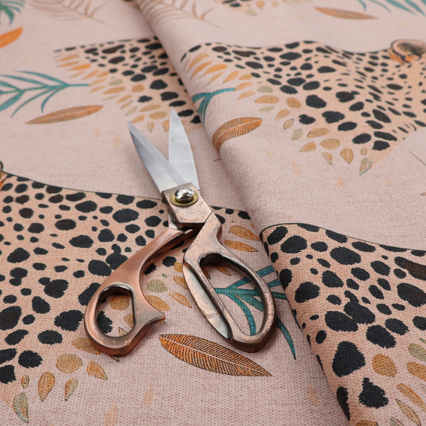 A pink fabric patterned with hand-drawn jungle illustrations of leopards and tropical leaves featuring an organic style.   