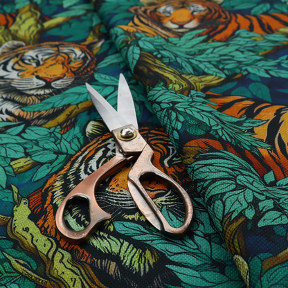 A dark blue fabric patterned with hand-drawn jungle illustrations of tigers nestled among dense green leaves featuring an organic style.