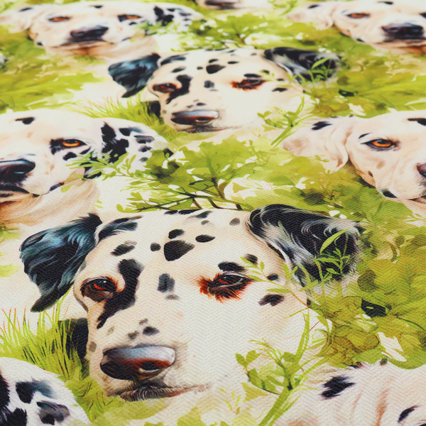A green and white fabric patterned with hand-drawn illustrations of Dalmatians nestled among lush foliage featuring an organic style.