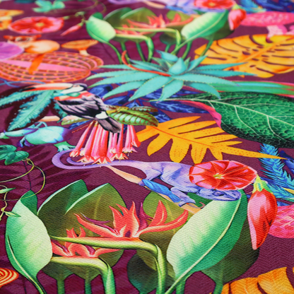 A burgundy fabric patterned with hand-drawn jungle illustrations of toucans, tarsiers, colourful birds, and tropical foliage featuring an organic style.   
