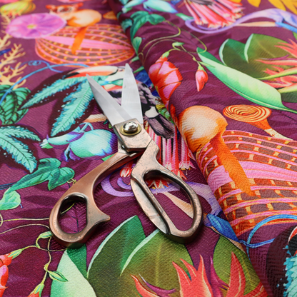 A burgundy fabric patterned with hand-drawn jungle illustrations of toucans, tarsiers, colourful birds, and tropical foliage featuring an organic style.   
