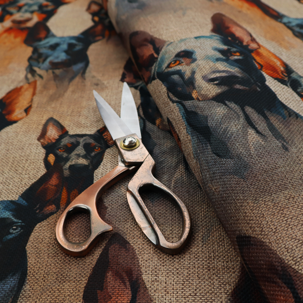 A repeating fabric pattern featuring portraits of Doberman dogs with pointed ears against a textured, burlap-like brown background.