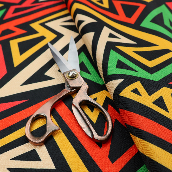 A repeating geometric fabric pattern on a black background featuring interlocking angular lines in red, yellow, green, and beige.