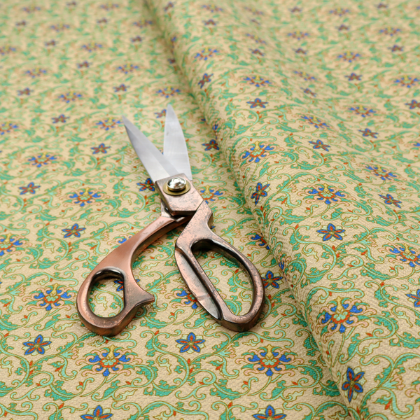 A dense, intricate fabric pattern featuring repeating blue and orange floral blossoms interwoven with teal scrollwork and leafy vines on a light gold background.