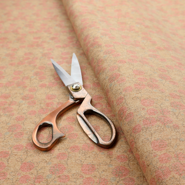 A beige fabric patterned with hand-drawn botanical illustrations of small pink flowers and vines featuring an organic style.