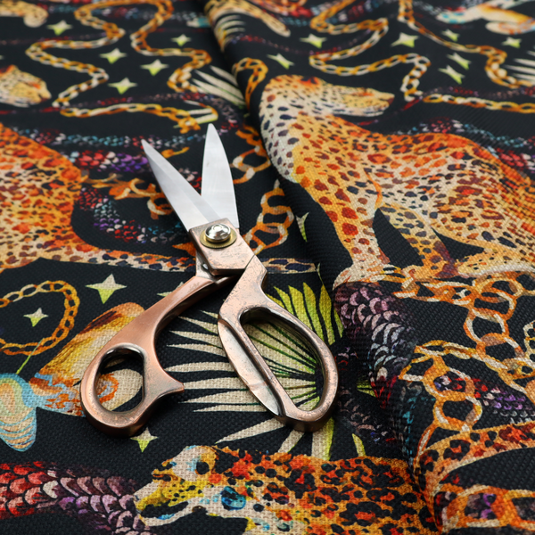 A dark blue fabric patterned with hand-drawn jungle illustrations of leopards, golden chains, tropical leaves, and butterflies featuring an organic style.   