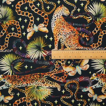 A dark blue fabric patterned with hand-drawn jungle illustrations of leopards, golden chains, tropical leaves, and butterflies featuring an organic style.   