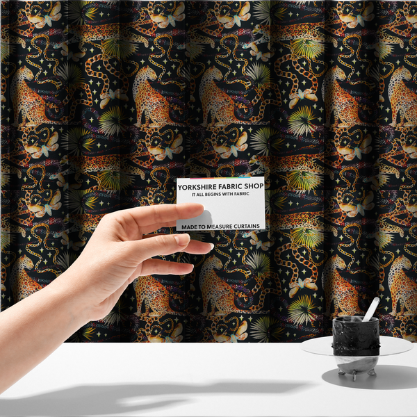The fabric used to create these made-to-measure curtains is a dark blue fabric patterned with hand-drawn jungle illustrations of leopards, golden chains, tropical leaves, and butterflies featuring an organic style.   