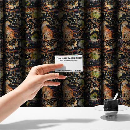 The fabric used to create these made-to-measure curtains is a dark blue fabric patterned with hand-drawn jungle illustrations of leopards, golden chains, tropical leaves, and butterflies featuring an organic style.   