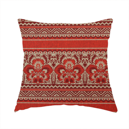 The fabric used to create this handmade cushion is fabric featuring a folkloric red and beige pattern with horizontal bands of floral motifs, chevrons, and dotted borders.