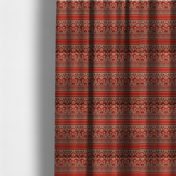 The fabric used to create these made-to-measure curtains is a fabric featuring a folkloric red and beige pattern with horizontal bands of floral motifs, chevrons, and dotted borders.