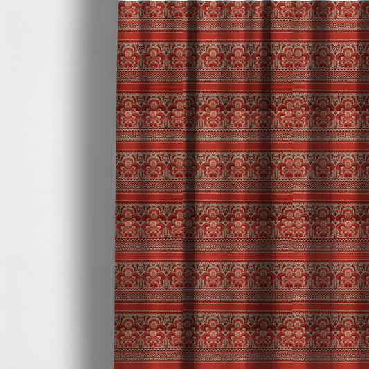 The fabric used to create these made-to-measure curtains is a fabric featuring a folkloric red and beige pattern with horizontal bands of floral motifs, chevrons, and dotted borders.