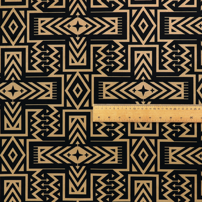 Black and gold geometric fabric featuring an intricate Navajo-inspired tribal pattern with chevron lines, diamonds, and cross motifs.