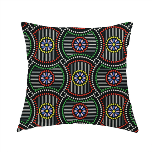 The fabric used to create this handmade cushion is a vibrant multi-coloured fabric featuring a detailed dotted pattern with concentric circular motifs, floral-like centre rosettes, and striped geometric panels in black, red, green, blue, and yellow.   