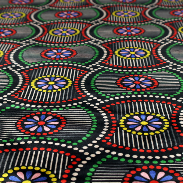 Vibrant multi-coloured fabric featuring a detailed dotted pattern with concentric circular motifs, floral-like centre rosettes, and striped geometric panels in black, red, green, blue, and yellow.   