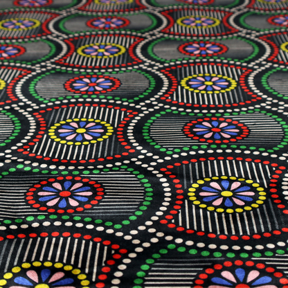 Vibrant multi-coloured fabric featuring a detailed dotted pattern with concentric circular motifs, floral-like centre rosettes, and striped geometric panels in black, red, green, blue, and yellow.   