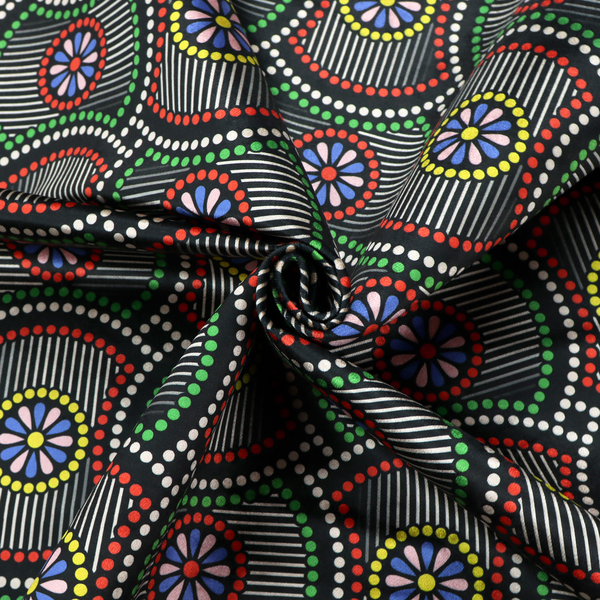 Vibrant multi-coloured fabric featuring a detailed dotted pattern with concentric circular motifs, floral-like centre rosettes, and striped geometric panels in black, red, green, blue, and yellow.   