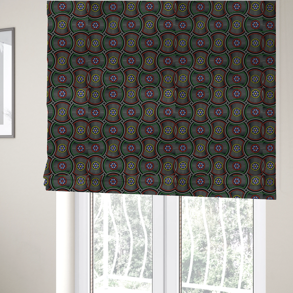 The fabric used to create these Roman blinds is a vibrant multi-coloured fabric featuring a detailed dotted pattern with concentric circular motifs, floral-like centre rosettes, and striped geometric panels in black, red, green, blue, and yellow.   