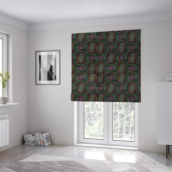 The fabric used to create these Roman blinds is a vibrant multi-coloured fabric featuring a detailed dotted pattern with concentric circular motifs, floral-like centre rosettes, and striped geometric panels in black, red, green, blue, and yellow.   
