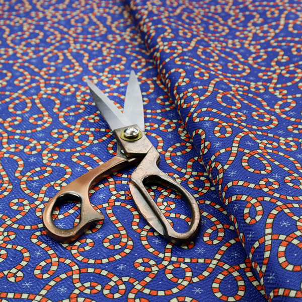 Blue and red fabric featuring an intricate festive pattern with continuous wiggly candy cane lines and tiny white snowflakes scattered across the deep blue background.   