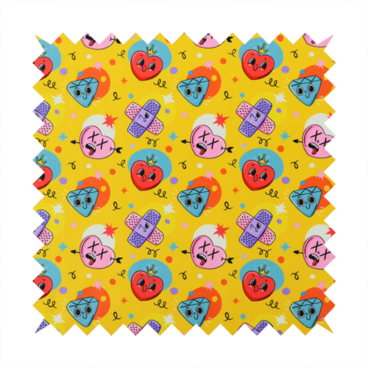 Yellow fabric featuring a playful, quirky pattern with cartoon-style graphics including smiling hearts with crowns, cute diamonds, cartoon bandages, and wacky faces with X eyes on a bright yellow background.   