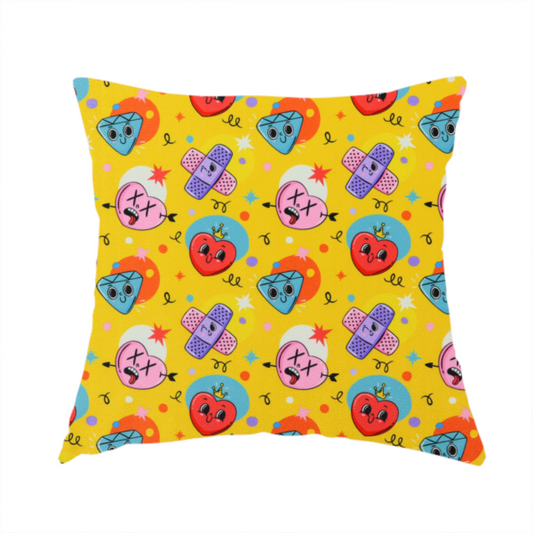 The fabric used to create this handmade cushion is a yellow fabric featuring a playful, quirky pattern with cartoon-style graphics including smiling hearts with crowns, cute diamonds, cartoon bandages, and wacky faces with X eyes on a bright yellow background.   