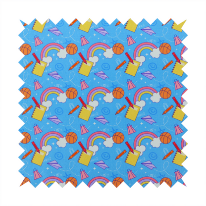 Blue fabric featuring a playful back-to-school pattern with colourful rainbows, basketballs, yellow notebooks with red pencils, purple paper airplanes, and school supplies scattered across a bright blue background.
