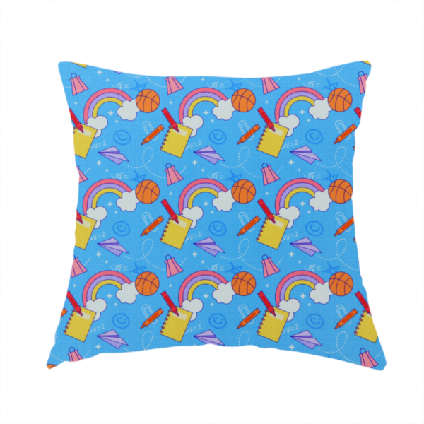 The fabric used to create this handmade cushion is a blue fabric featuring a playful back-to-school pattern with colourful rainbows, basketballs, yellow notebooks with red pencils, purple paper airplanes, and school supplies scattered across a bright blue background.