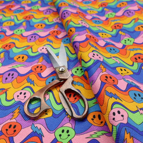 Multicolour fabric featuring a psychedelic groove pattern with wavy horizontal stripes in shades of blue, purple, green, yellow, and orange, interspersed with smiling smiley faces and lightning bolts.