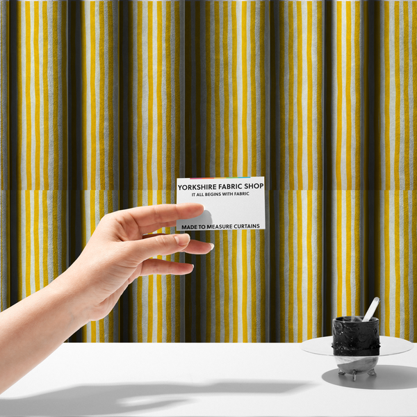 The fabric used to create these made-to-measure curtains is a white fabric patterned with vertical, hand-drawn yellow stripes that feature a slight, organic waviness.   
