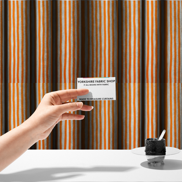 The fabric used to create these made-to-measure curtains is a white fabric patterned with vertical, hand-drawn orange stripes that feature a slight, organic waviness.