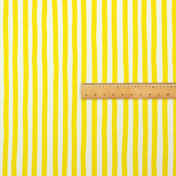 A white fabric patterned with vertical, hand-drawn yellow stripes that feature a slight, organic waviness.