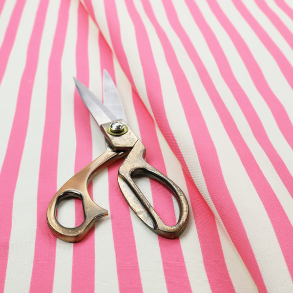A white fabric patterned with vertical, hand-drawn pink stripes that feature a slight, organic waviness.