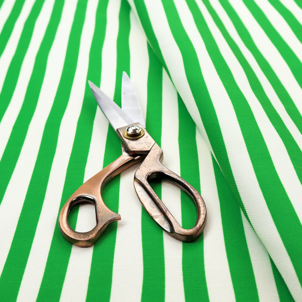 A white fabric patterned with vertical, hand-drawn green stripes that feature a slight, organic waviness.