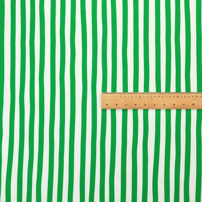 A white fabric patterned with vertical, hand-drawn green stripes that feature a slight, organic waviness.